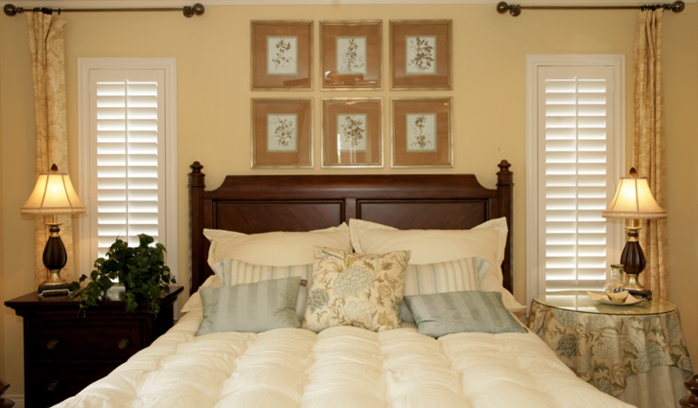 Bedroom with two tall plantation shutters on either side of bed in Austin 